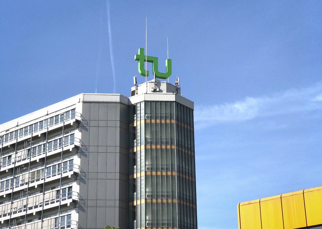 Foto des TU Gebäudes mit dem TU-Logo auf der Spitze des Gebäudes