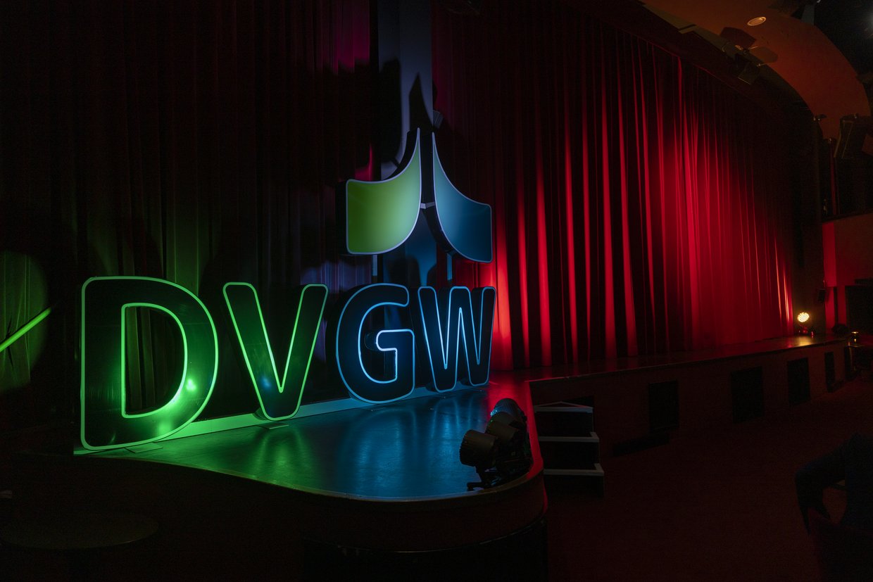 Das dreidimensionale Logo des DVGW wird von grünen und blauen Scheinwerfern auf einer Bühne beleuchtet