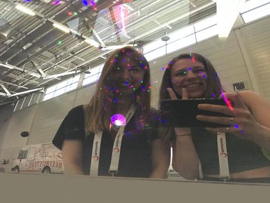 Eugenie und Kathrin machen ein Selfie, indem sie ihr Spiegelbild auf der Scheibe des H2ero-Fahrzeuges abfotografieren.