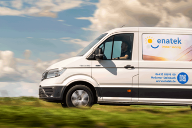 Der enatek-Transporter mit Branding fährt bei Sonnenschein über eine Landstraße